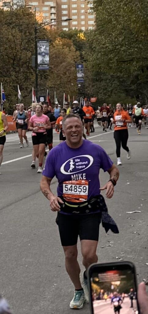 Smiling runner during race with runners and city buildings in the background